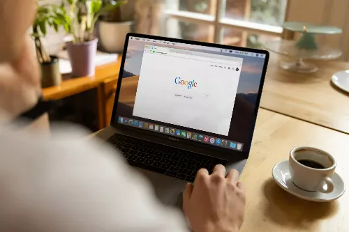 man achter een laptop met een kop koffie